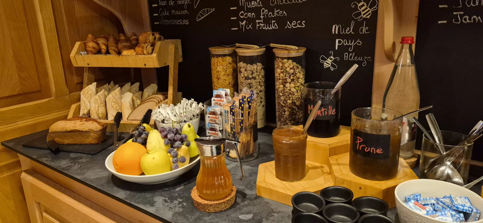 Viennoiseries, pains, fruits frais et confitures maison au buffet du petit-déjeuner