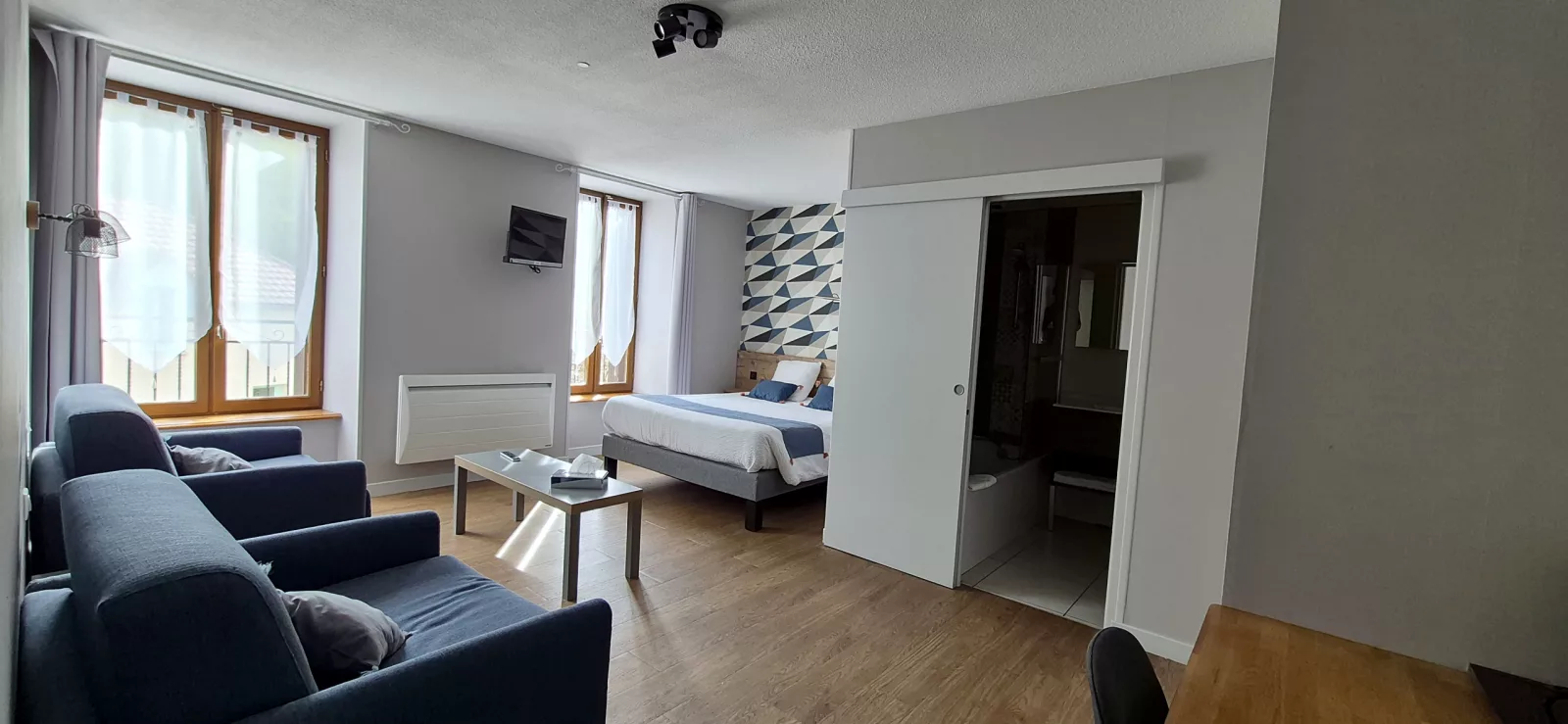 Grande chambre bleue avec coin salon, deux canapés et salle de bain attenante