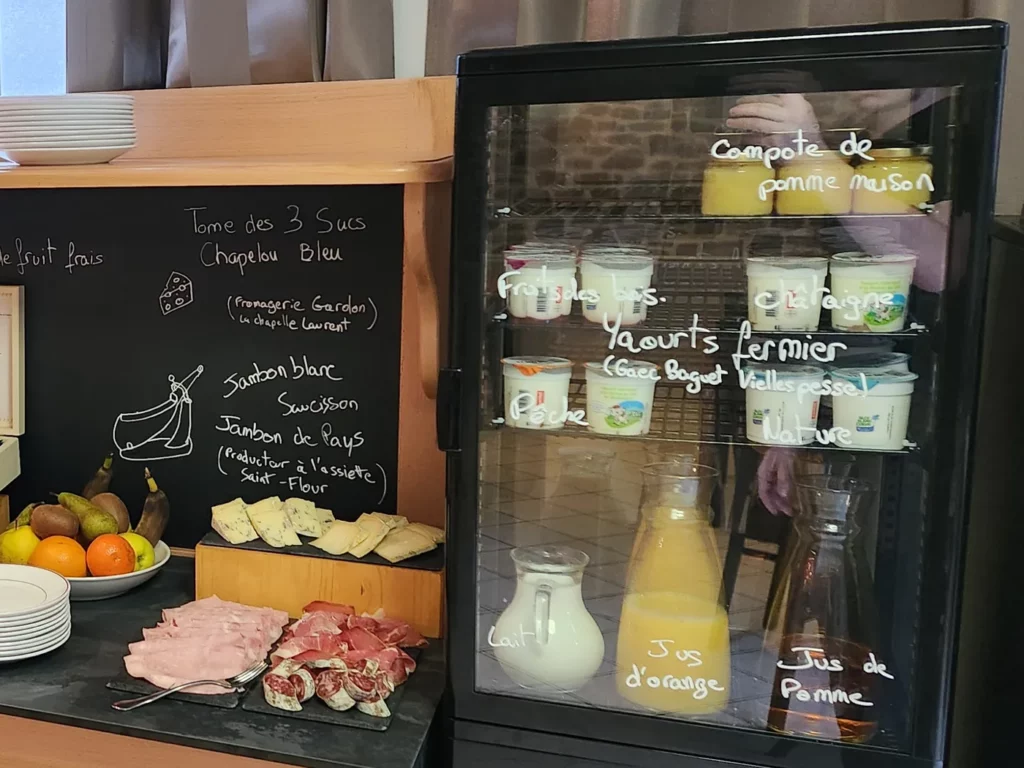 Vitrine réfrigérée du buffet : yaourts fermiers, compote de pomme maison, lait, jus d'orange et jus de pomme