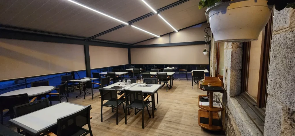 Intérieur de la terrasse : tables dressées, plancher bois, stores et éclairage LED